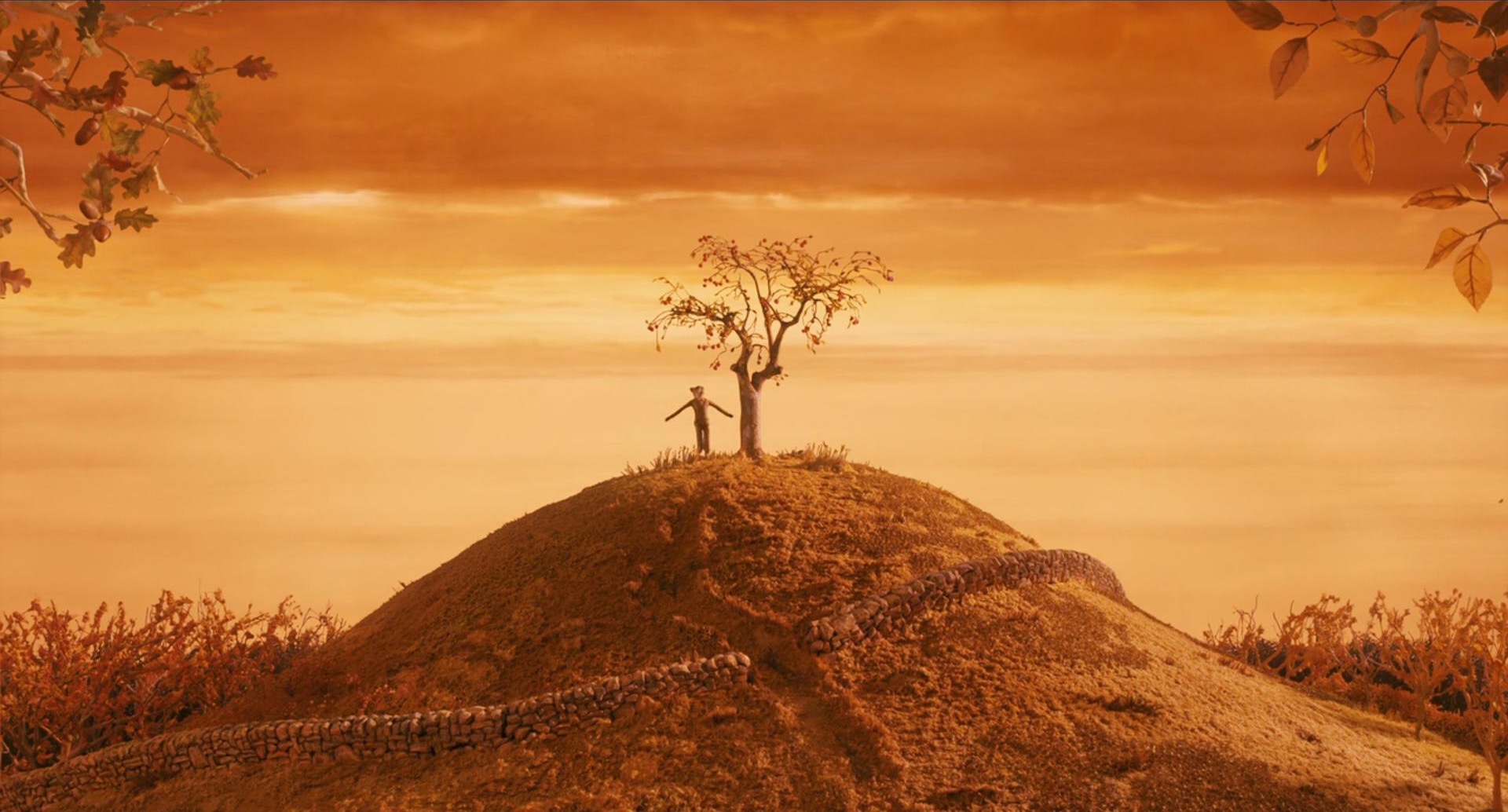 landscape photo of a tree on the top of a hill with mr.fox standing beside it